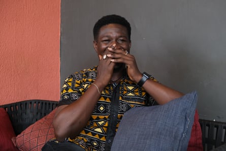 A man sits on a sofa covering his mouth and nose with his hands.