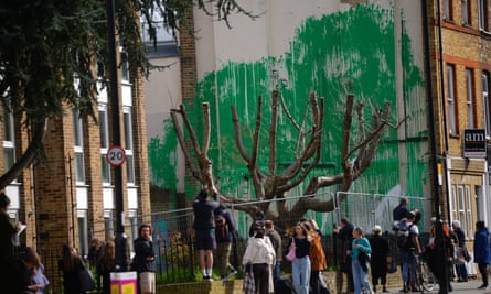 People looking at the damaged Banksy artwork.