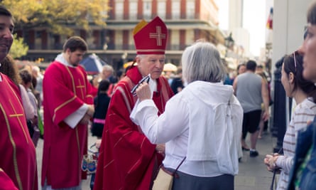 Older white man with red pointy had and reb robes, flanked by two younger white men with no hats and red robes, speakers with a white woman with tidy gray hair and white shirt outside.