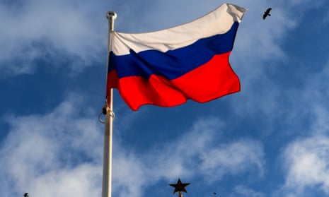 A Russian national flag flies in front of one of the Kremlin ruby stars in downtown Moscow
