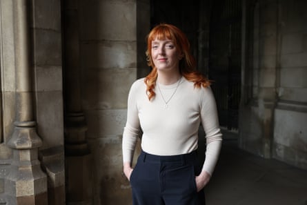 Charlotte Nichols stands in a stone courtyard in Westminster. She is in her mid-30s and has long red hair with a fringe across her forehead. She wears a pale cream ribbed jumper and dark trousers.