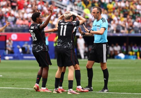 Players surround referee Joao Pinheiro to appeal for a penalty.