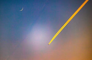 Newbury, UK. A plane flies west over Berkshire beneath a new moon