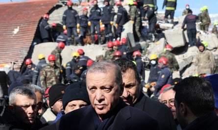 Turkey's Erdoğan in front of a destroyed building and surrounded by people