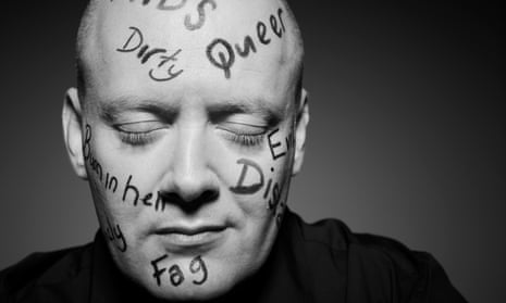 Matthew Todd, eyes closed, with words like 'dirty', 'queer', 'fag' and 'Aids' written in pen on his face and shaved head