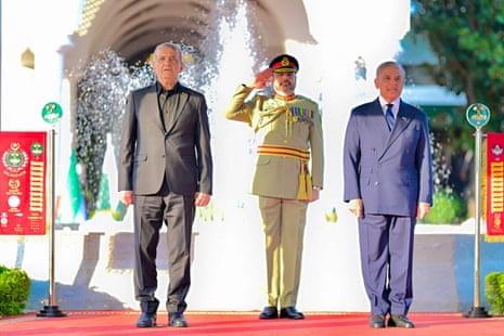 Pezeshkian stands next to Shehbaz Sharif, a saluting Pakistani guard between them.