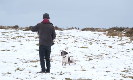 Dog walker in snow in Dartmoor.