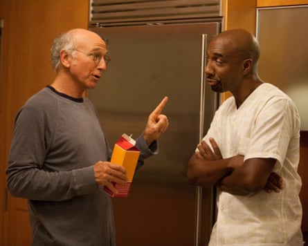 White man points at Black man next to fridge