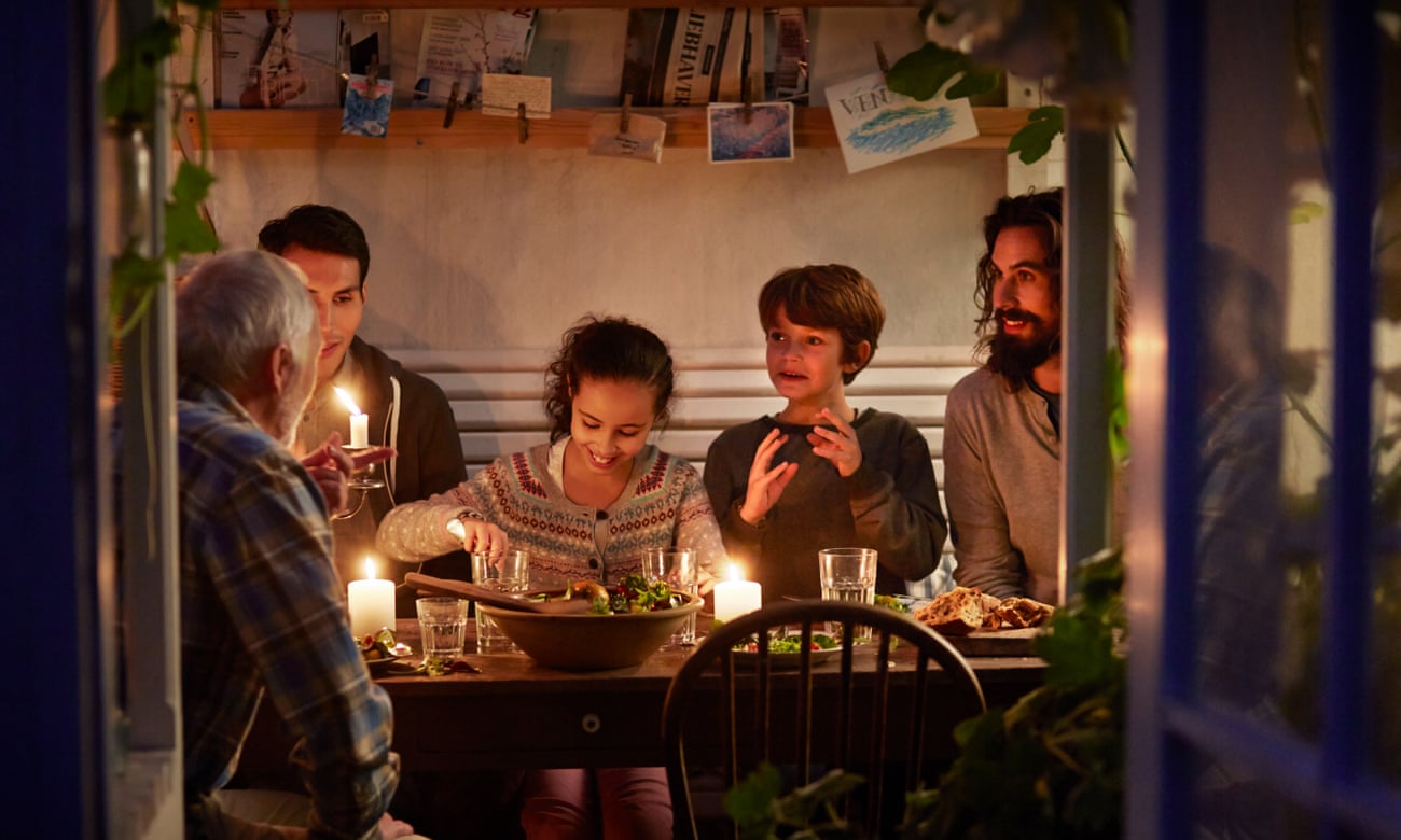 A family relaxing together around a candlelit table epitomises hygge.