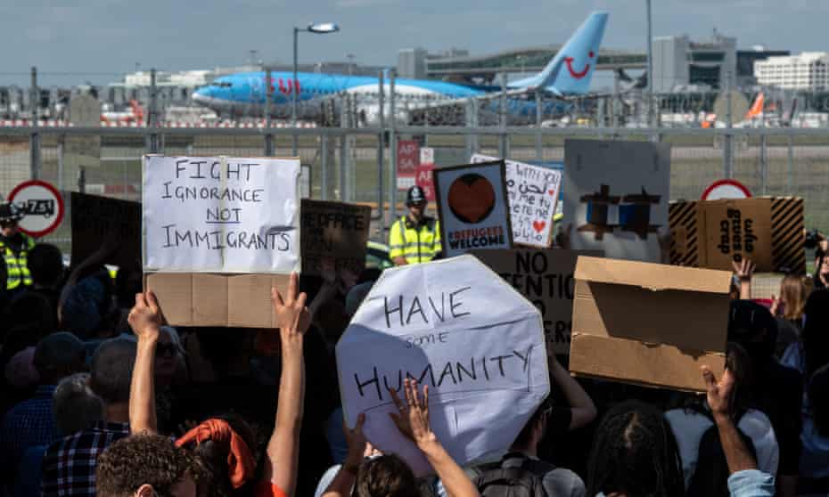Protesters near Brook House immigration removal centre hold placards protesting against UK deportation flights to Rwanda