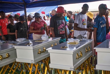 Family members walk past caskets carrying their loved ones during a memorial service for the victims