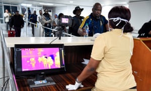A Port Health Service staff member stands next to a thermal scanner as passengers arrive at Murtala Mohammed International airport in Lagos, class=