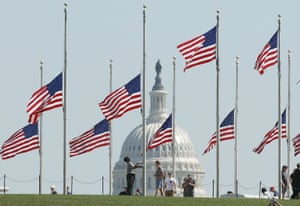A National Park Service worker lowers US flags to half mast on the grounds of the Washington Monument