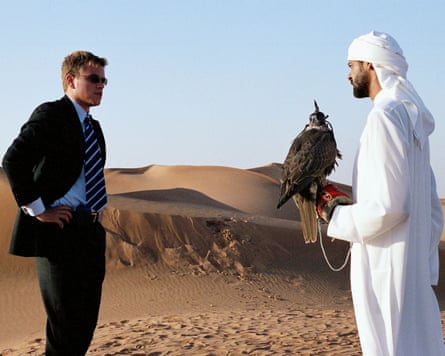 Man in suit and man in thobe holding bird of prey