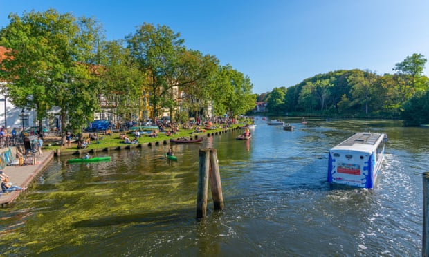 A bus, not far from a riverbank, up to its wheels in the water