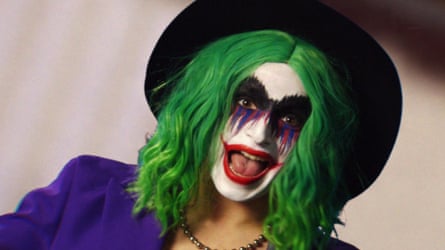 person in green wig, clown makeup and hat