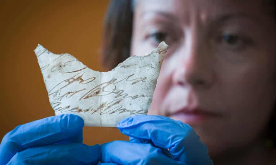 Curator Anna Forest examines a fragment of an 18th-century handwritten document discovered under the floorboards of Oxburgh Hall, Norfolk.