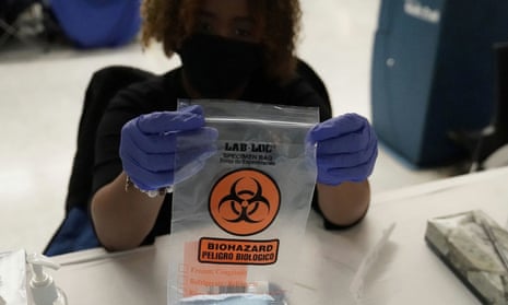 A worker holds up a biohazard bag containing a coronavirus test swab in New York City. This new rise in cases is most pronounced in Michigan and New York.