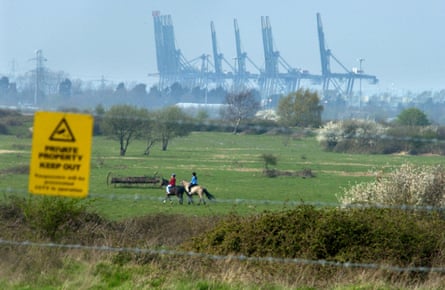 Horseriders on the fenced off site with the giant cranes of the container port in Southampton Docks in the background