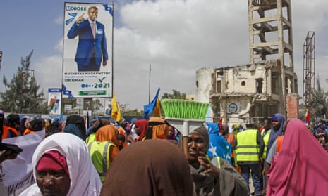 Somalis walk past a billboard showing a presidential candidate Omar Abdulkadir Ahmedfiqi in Mogadishu.
