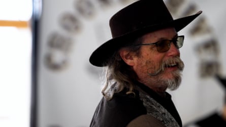 A man wearing sunglasses and a cowboy hat looks off to the side.