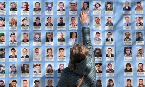 A woman touches a picture of her dead son at the Memory Wall of Fallen Defenders of Ukraine in Kyiv, 14 March 2023.  
