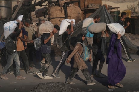 Palestinians carry sacks of flour unloaded from a humanitarian aid convoy that reached Gaza City on Saturday.