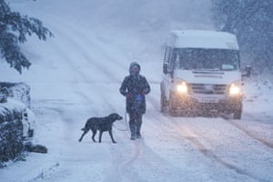 Northumberland, UK: A dog walker and a van driver make their way along a snow-covered road in Slaley. Parts of the UK could be blanketed with up to 20cm (7ins) of snow in the coming days