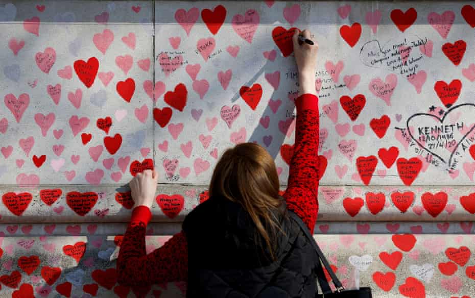 A person writes a message on the National Covid Memorial Wall, March 2022