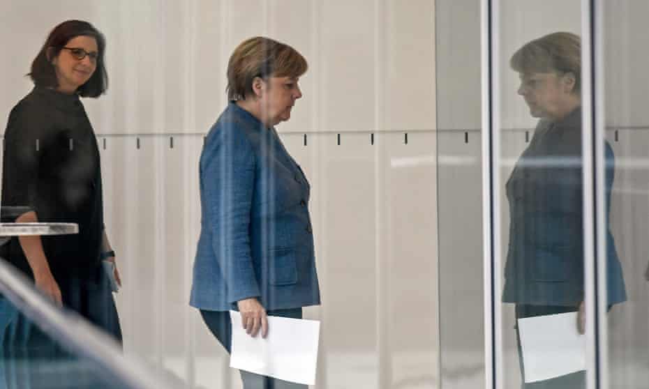 Angela Merkel is followed through a glass corridor by the Green party co-leader Katrin Göring-Eckardt