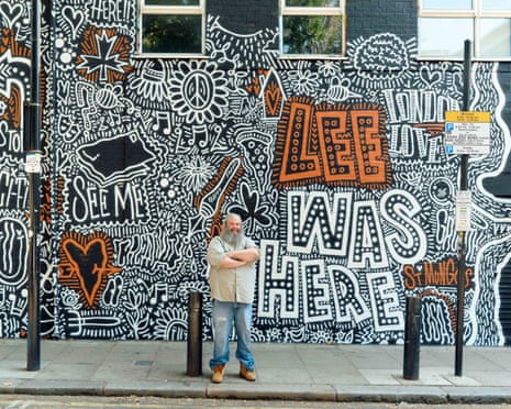 Lee, a St Mungo’s case study, stands on the street in front of his dedicated mural, which reads 'Lee was here' in large letters