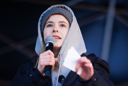 Luisa Neubauer in a warm hat and hoodie giving a speech with a microphone