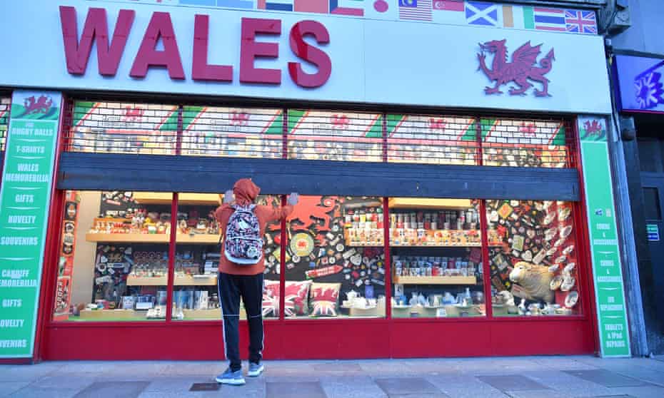 Shop owner pulls the shutters down on the Wales souvenir shop in Cardiff before Wales entered a two-week lockdown.