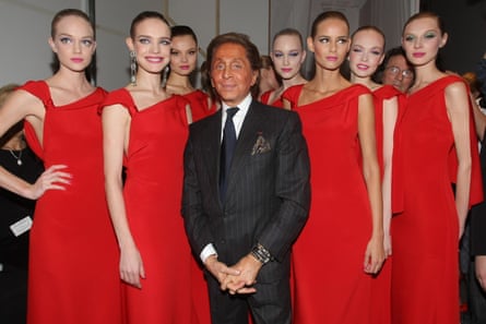 Valentino stands in front of models wearing the same red dress, in 2008