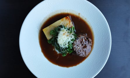 Poitrine de boeuf en sauce noire sur une grande assiette blanche ronde.