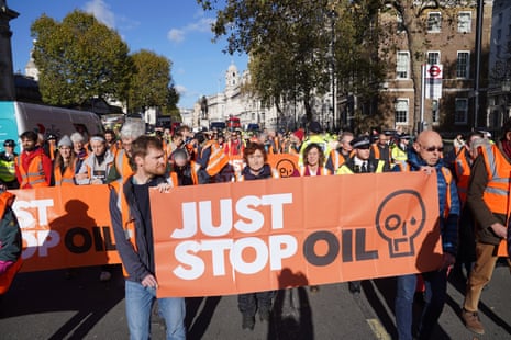 Protesters hold a Just Stop Oil banner walking in the middle of a road