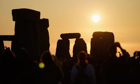 The standing stones are silhouetted against the  sky, the rising sun in the background, as people gather to take part in the summer solstice at Stonehenge in Wiltshire this year.