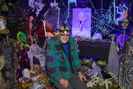 a man in a checkered shirt poses for a portrait next to Halloween decorations