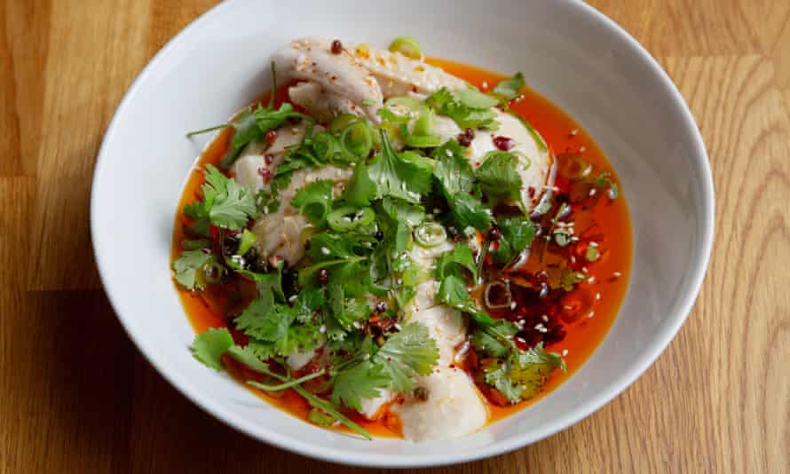 Appetizing chicken in a red sauce with cilantro on top in a round white bowl