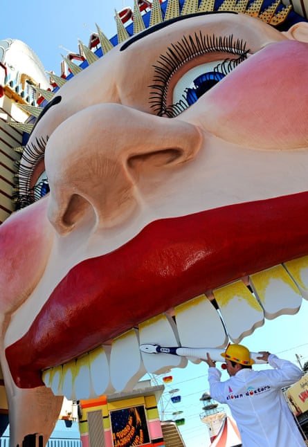 Clown Doctor, Dr B Looney, uses a giant oversized toothbrush to clean the teeth of the iconic face at the entrance to Sydney’s Luna Park on April 1, 2010.