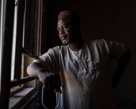 Umar Bio Salihu, head of the village of Woro looks across a window