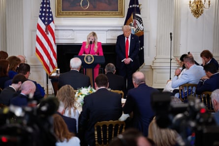 Woman in pink, man in black suit, at lectern in room.