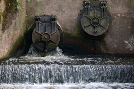 Water discharges from an outlet pipe into a river
