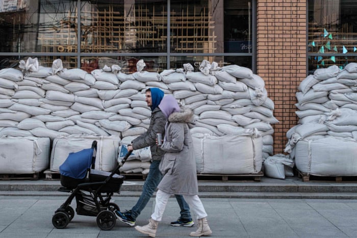 A couple walk in front of a shop covered by sandbags in Dnipro, Ukraine.