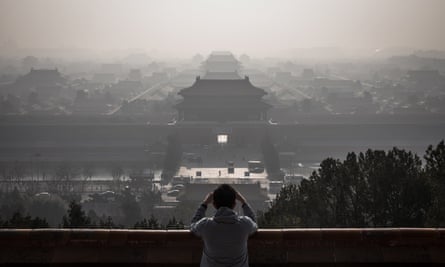 A man standing at a viewing area of Jingshan Park takes photos of the Forbidden City as a thick haze engulfs Beijing