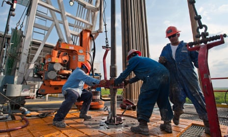 Workers wrestle with a pipe on an oil rig in Texas.
