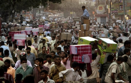 A shopkeeper sits on boxes as he waits for transportation at a busy wholesale market in New Delhi, India. 