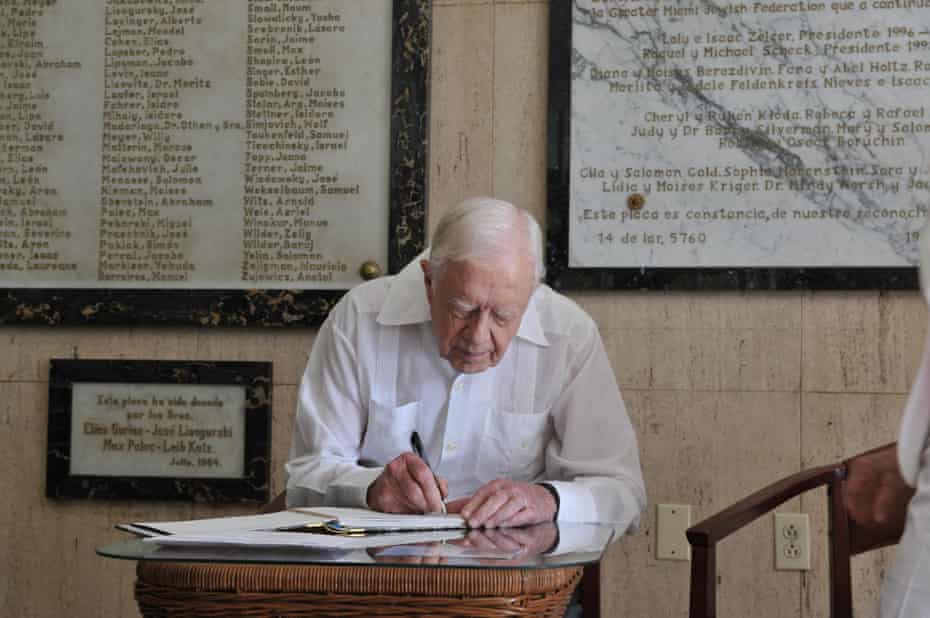 Former US President Jimmy Carter writes in the guest book at the end of his visit to the Cuban Jewish Community centre in Havana, on March 28, 2011.