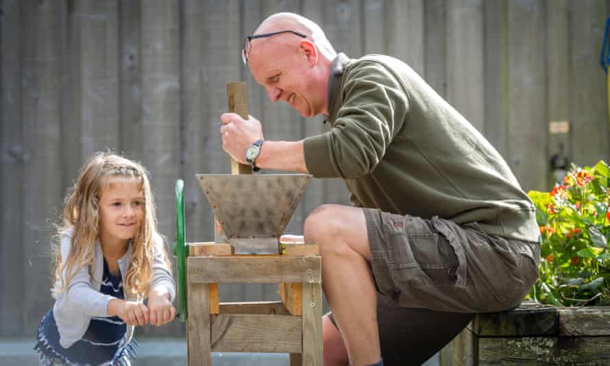 A man and young girl operating an apple press