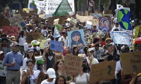 People march along Reforma Avenue with signs during a climate protest in Mexico City